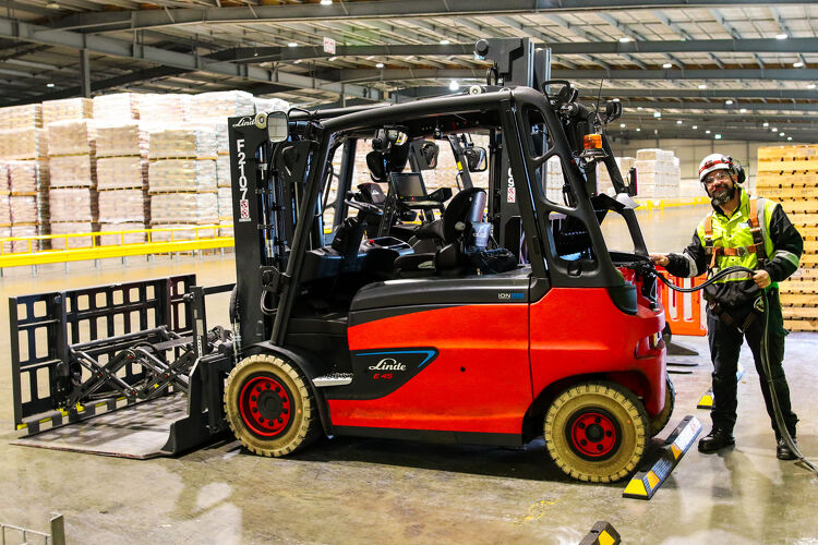 Warehouse worker operating an electric forklift beside stacked pallets