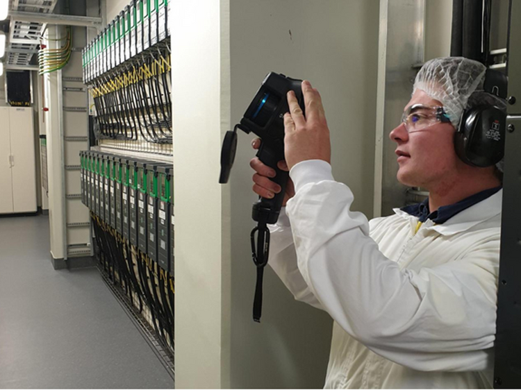 Technician using a thermal imaging camera on server room cabling