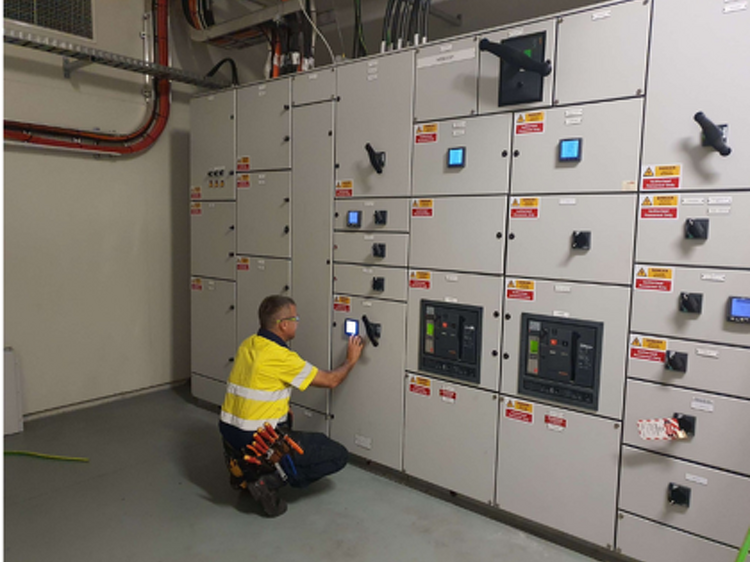 Technician using a thermal imaging camera to inspect a switchboard panel
